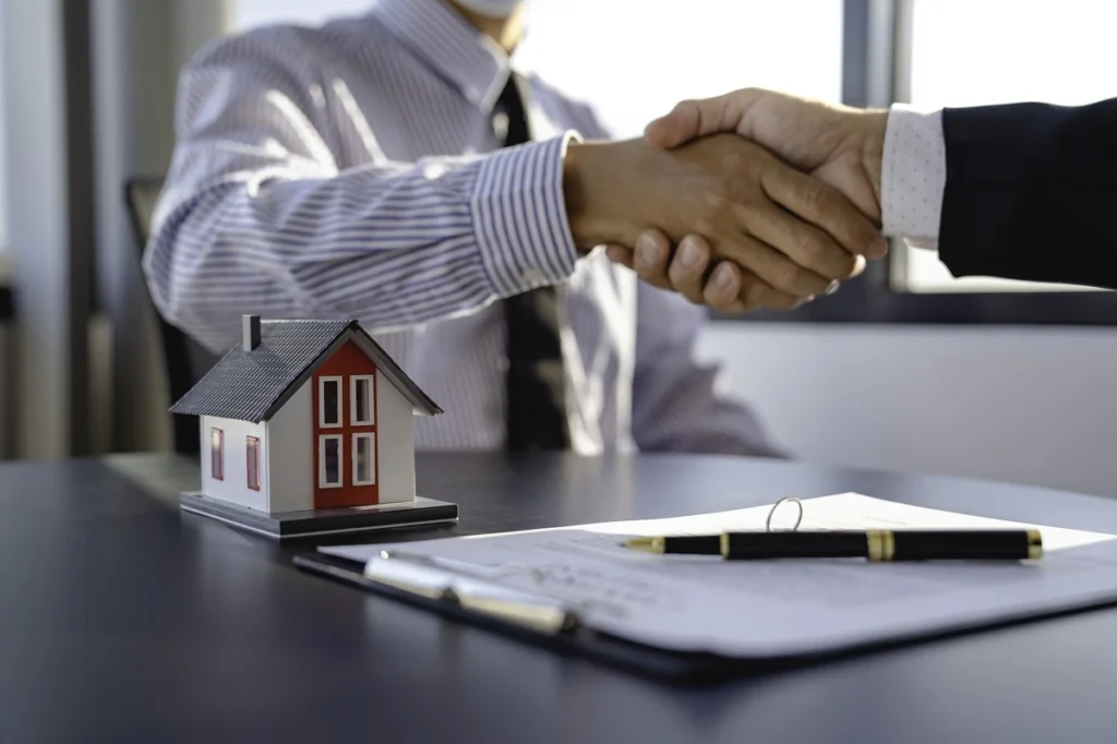 Mortgage Advisor and client shake hands over mortgage documents after approval.